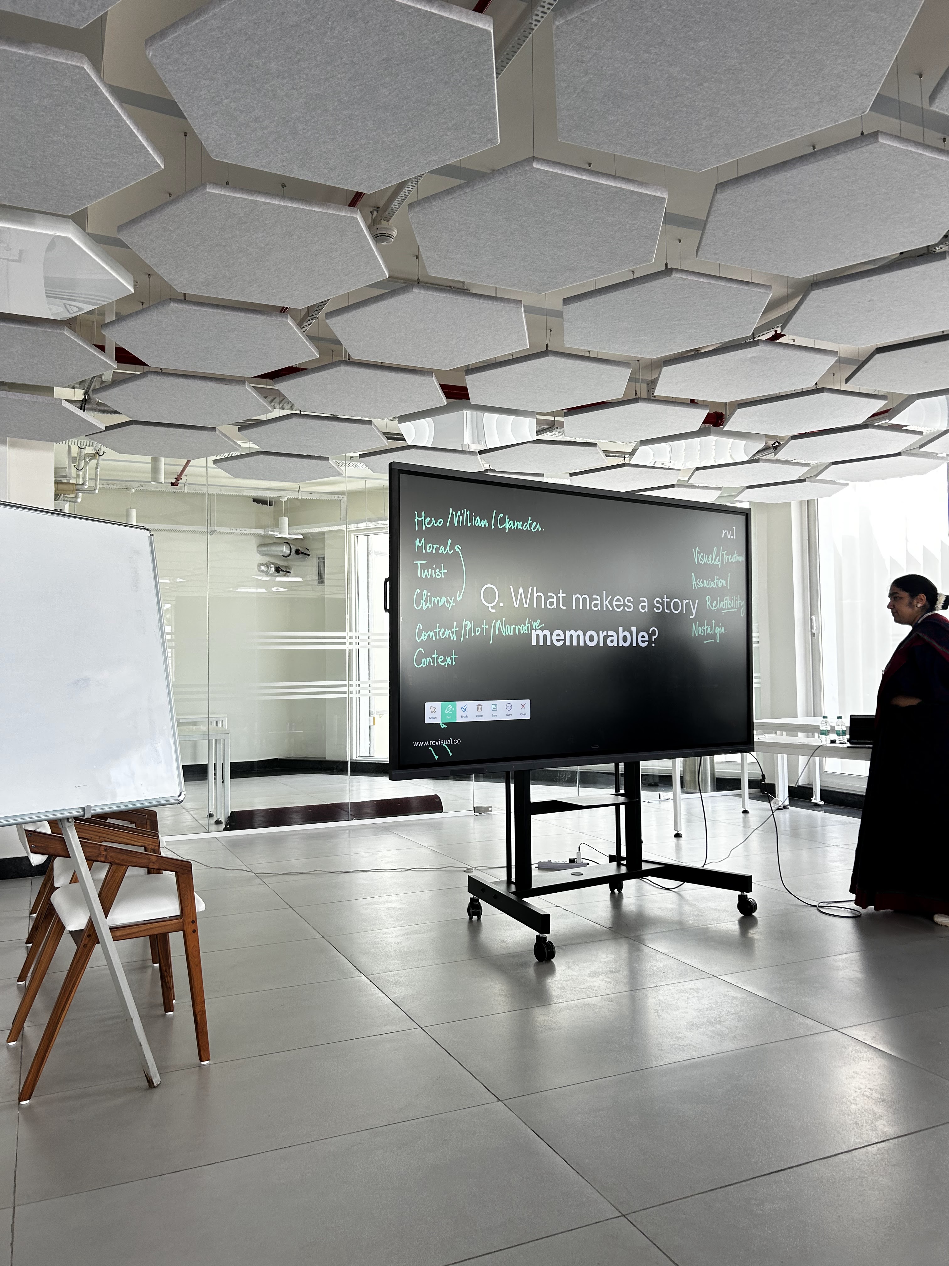 A large screen in the workshop reads "What makes a story memorable?", surrounded by handwritten notes like Hero, Villain, Twist, Climax, Nostalgia.